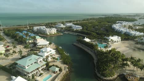Aerial-View-of-Resort-on-Knight's-Key-in-Marathon-Florida-With-Fishing-Boat-and-Palm-Trees-Blowing-in-Wind-and-Ocean-in-Background-Pan-Up