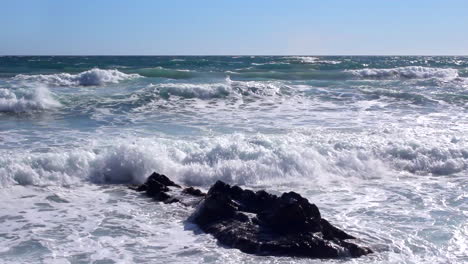 Rough-sea-waves-splashing-on-the-rocks-and-on-the-beach