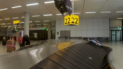 Ankunft-Des-Gepäcks-Vom-Förderband-Aus-Gesehen,-Das-Mit-Wenig-Gepäck-In-Einen-Fast-Leeren-Gepäckausgabeflur-Des-Internationalen-Niederländischen-Flughafens-Schiphol-Gelangt