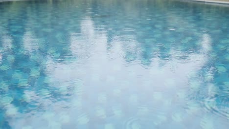 Regentropfen-Fallen-Auf-Die-Oberfläche-Eines-Schwimmbades-In-Zeitlupe