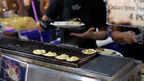 Street-food-on-grill-ready-to-serve-by-woman,-Bangkok-night-market