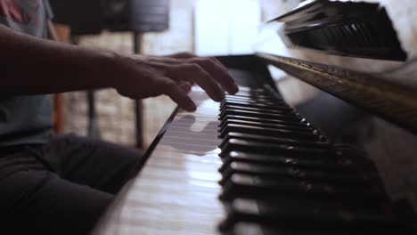 Male-musician-plays-an-old-vintage-Yamaha-piano,-side-view-with-shallow-depth-of-field-4K