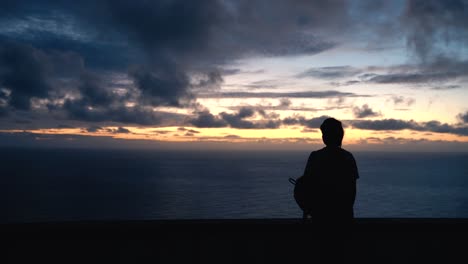 Silhouette-of-young-woman-watching-a-sunset-over-ocean,-Medium-shot