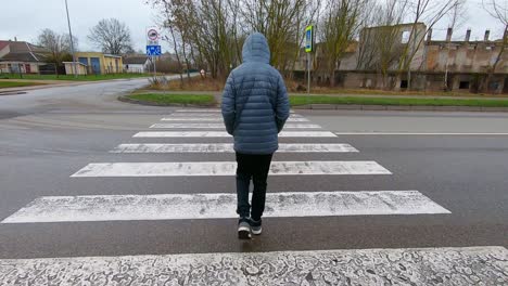 A-Teenager-Walks-Through-a-Pedestrian-Crossing-on-a-Rainy-Day