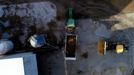 Drone-top-down-shot-of-payloader-loading-cattle-wagon-as-farmers-do-their-daily-morning-chores-feeding-cattle