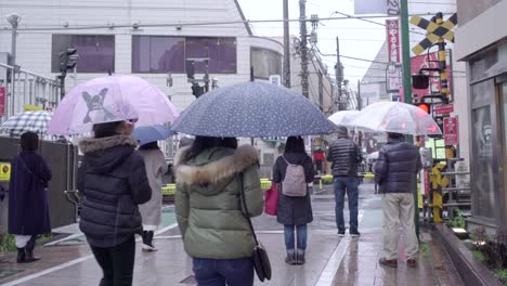 Gente-Cruzando-El-Ferrocarril-Y-Caminando-En-Una-Calle-Estrecha-En-Tokio,-Japón---Lapso-De-Tiempo