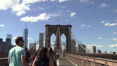 Touristen-Gehen-An-Einem-Sonnigen-Tag-über-Die-Brooklyn-Bridge,-Im-Hintergrund-Der-Manhattan-Freedom-Tower