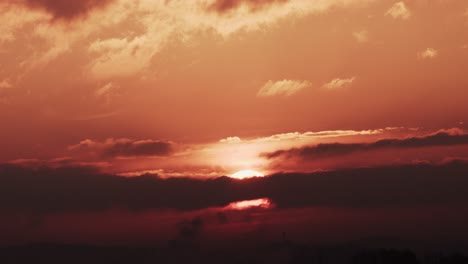 Time-lapse-of-epic-sunrise-rising-above-clouds-with-fiery-glow,-burning-red-sun
