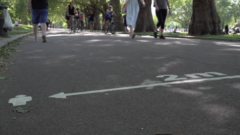 People-walk-and-cycle-past-pavement-markings-in-a-park-that-show-two-metre-social-distancing-during-the-Coronavirus-outbreak