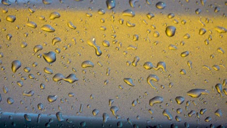 Water-drops-on-metallic-surface-in-orange-teal-tones-during-rain