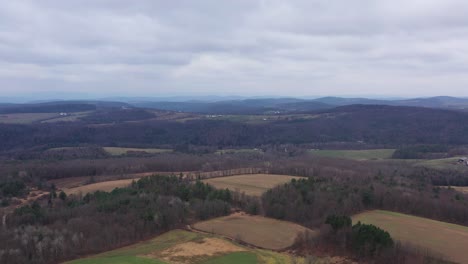 Aerial-flyover-beautiful-Pennsylvania,-USA-countryside-with-hills-in-background-and-forest-during-cloudy-sky