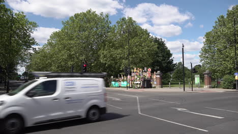 Vehicles-cross-a-road-junction-past-a-huge-memorial-wall-of-cardboard-signs-showing-support-of-healthcare-staff-during-the-Coronavirus-outbreak-line-the-edge-of-a-park-in-the-East-End-of-London