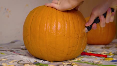 Pumpkin-Carvin-Female-Cutting-out-Cute-Face-of-Jack-O'Lantern-into-Pumpkin-with-knife-getting-it-ready-as-Halloween-decoration