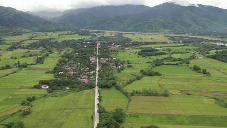 Farm-to-market-road-heading-to-mountainous-terrain-aerial-shot