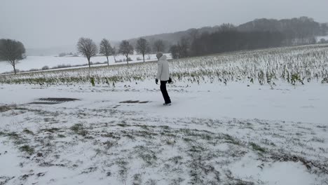 Girl-In-Winter-Clothes-Walking-In-Snow-Covered-Field-During-Winter-In-Germany---wide-shot