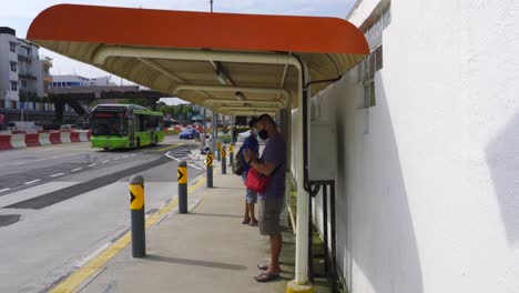 Chinese-man-wearing-face-mask-and-using-mobile-phone-while-wait-for-bus-in-Singapore,-Asia