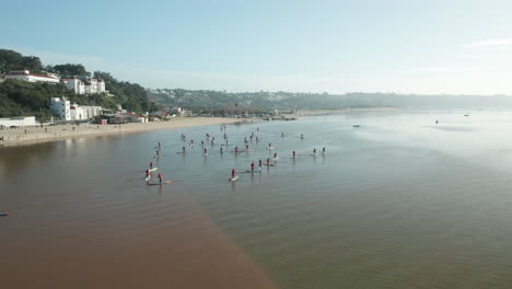 Stand-Up-Paddle-Board-Scenery-In-Santa-Claus-Attire-In-The-Beautiful-Water-Of-Obidos-Lagoon-During-Winter-In-Portugal