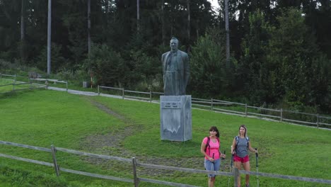 Pull-back-aerial-shot-of-hikers-walking-and-standing-near-the-Lovro-Kuhar-Statue