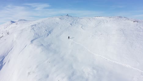 Skier-surviving-the-cold-of-Hamlagro-Bergsdalen-Norway---Climbing-up-snowy-hill-to-reach-mountain-top-on-a-clear-day-with-blue-sky