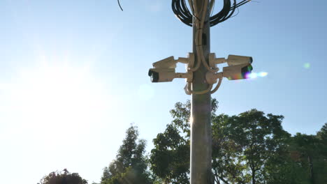 wide-shot-of-security-cameras-on-a-post-from-left-with-the-sun-in-the-back