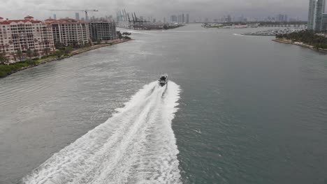 Aerial-View-of-Boat-Driving-through-Ocean-in-City-Skyline