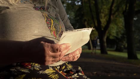 Mature-woman-reading-letter-in-the-park-zoom-in-shot