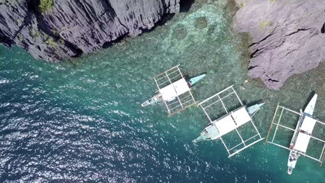 Vista-Aérea-De-Arriba-Hacia-Abajo-De-4k-De-Los-Barcos-Estabilizadores-De-Banca-En-La-Isla-Miniloc-En-Filipinas-En-Hermosas-Aguas-Tropicales-Azules
