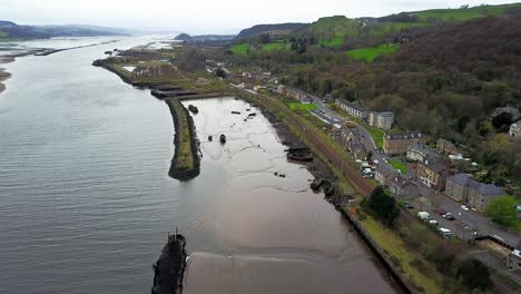 Stranded-old-boat-wreckage-covered-with-mud-visible-by-the-low-water-of-the-river-Clyde-at-Bowling-harbour-in-West-Dumbartonshire-Scotland