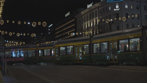 Two-trams-pass-on-a-street-decorated-with-Christmas-lights-at-night