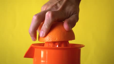 Eine-Orange-In-Einem-Manuellen-Entsafter-Mit-Der-Hand-Auspressen