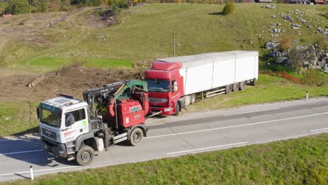 Aerial-view-of-towing-truck-tows-a-broken-down-long-lorry-truck-in-a-mountain