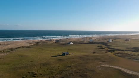 houses-located-on-the-coastal-beach-of-Rancho-Uruguay,-water-waves-moving-towards-the-dry-land-of-the-coastal-beach-of-Uruguay