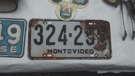Top-view-circle-pan-shot-of-rusty-car-license-plate-at-Feria-Tristan-Narvaja