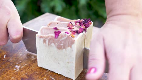 A-women-gently-slices-a-newly-made-block-of-handmade-soap-with-a-sharp-knife