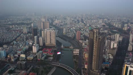 Flying-along-Ben-Nghe-Canal-in-Saigon-over-high-rise-buildings-and-view-to-urban-sprawl-of-Ho-Chi-Minh-City,-Vietnam-Part-one