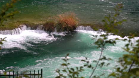 View-of-a-waterfall-flowing-from-a-large-blue-pond-to-another-blue-pond-in-Krka-National-Park-in-Croatia