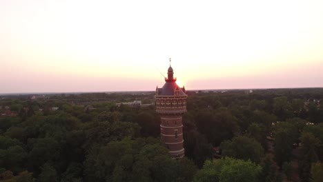Eine-Umlaufbahn-Mit-Niedrigem-Winkel-Um-Einen-Wasserturm-Mit-Hellem-Sonnenuntergang-Im-Hintergrund