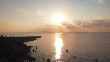 Aerial-drone-shot-rising-over-Konnos-Bay-coast-with-golden-sunset