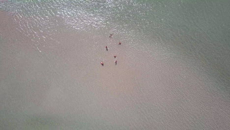 Rotating-drone-view-of-a-group-of-people-relaxing-by-the-beach-of-a-calm-peninsula