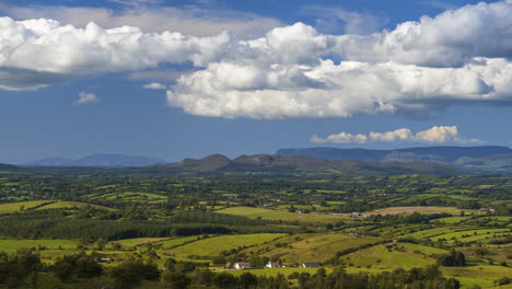 Zeitraffer-Einer-Ländlichen-Agrarlandschaft-Mit-Grünen-Feldern,-Wäldern,-Hügeln-Und-Bauernhäusern-An-Einem-Sonnigen-Sommertag-In-Irland