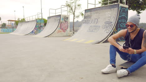 Young-boy-using-cell-phone-on-a-skate-park