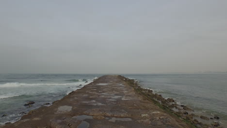 Shot-over-a-seawall-path-passing-by-some-fisherman's-in-Costa-de-Caparica,-Almada,-Lisbon