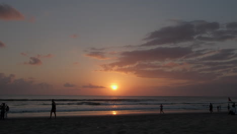 Bali-Kutha-Strand-Sonnenuntergang-Mit-Menschen-Zu-Fuß-Silhouette-Wolken-Himmel-Sand-Und-Meer