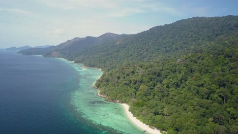 Aerial-view-of-long-lush-island-with-vegetation-and-beautiful-waters-in-Thailand---lateral-tracking-shot-slightly-panning-left