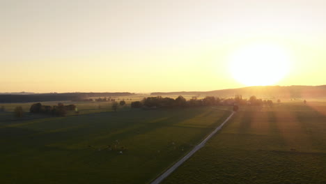 Schwenk-über-Landwirtschaftliche-Felder-Mit-Dem-Sonnenuntergang-über-Den-Bergen-Im-Hintergrund,-Bayern,-Deutschland
