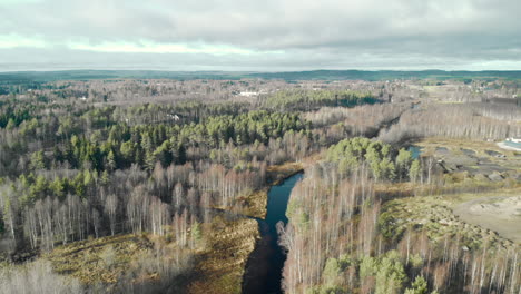 Aerial,-drone-shot,-flying-towards-a-river,-in-a-leafless,-autumn-forest,-on-a-cold,-half-cloudy,-fall-day,-in-Juuka,-North-Karelia,-Finland