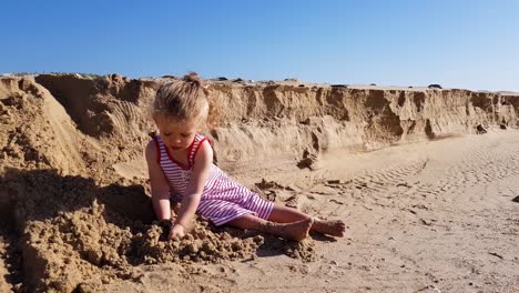 Toddler-girl-is-playing-with-sea-sand-on-the-beach-and-having-fun