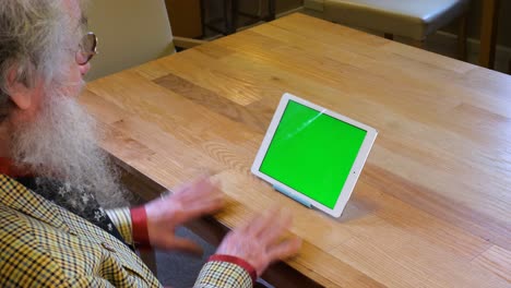 Older-man-with-beard-talking-to-tablet-greenscreen