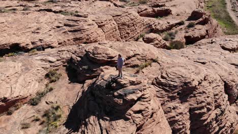 Drone-circles-around-person-standing-on-red-rock-formation