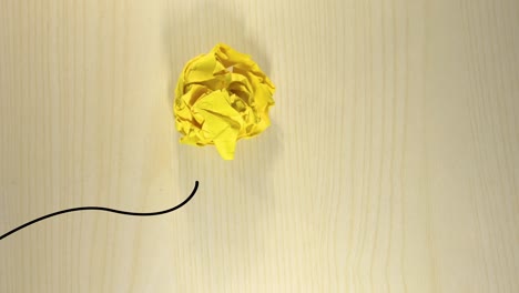 yellow-crumpled-paper-ball-being-throwed-away,-landing-on-a-light-wooden-background,-cartoon-animated-lines-creating-a-light-bulb-with-rays-from-it